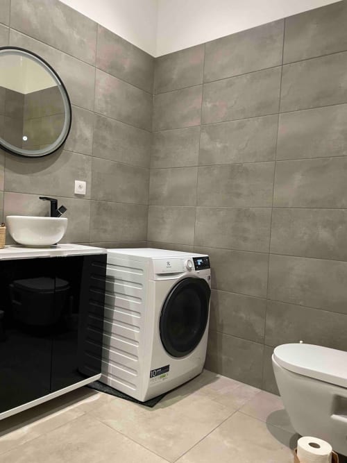 Salle de bain moderne à Illkirch-Graffenstaden avec carrelage gris, lave-linge blanc, vasque et toilettes