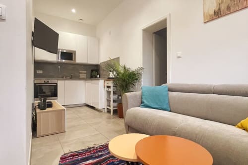 Espace de vie moderne avec cuisine, canapé gris et accents colorés à Illkirch-Graffenstaden