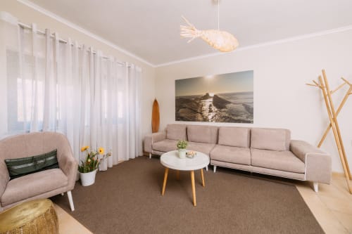 Sala de estar moderna em tons bege do hotel Casa da Praia em Zambujeira do Mar com sofá, poltrona e obra de arte marinha