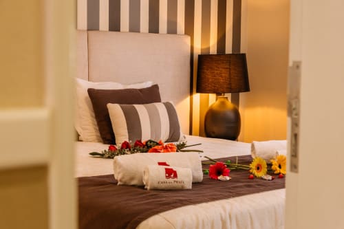 Quarto elegante do hotel Casa da Praia em Zambujeira do Mar com cabeceira listrada, flores decorativas e iluminação acolhedora