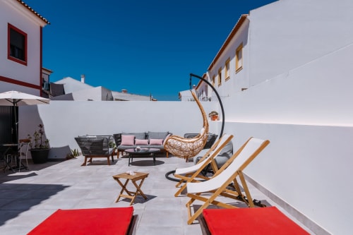 Terraço ensolarado no telhado do hotel Casa da Praia em Zambujeira do Mar com espreguiçadeiras de madeira, área de estar e vistas para o oceano