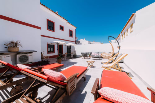 Terraço ensolarado da Casa da Praia com espreguiçadeiras, zona de estar e céu azul em Zambujeira do Mar