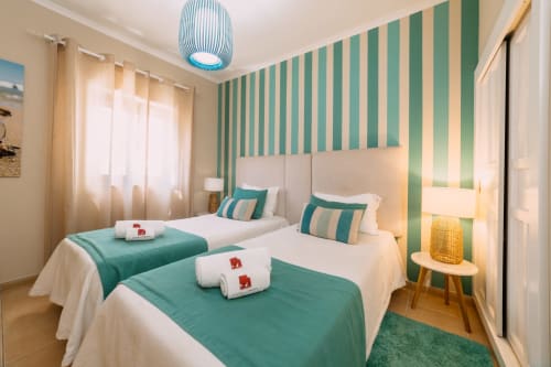 Camas gêmeas com parede de acentuação em listras verdes e brancas no hotel Casa da Praia em Zambujeira do Mar