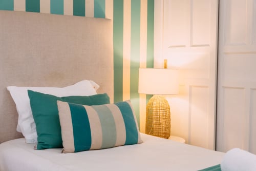 Modern beach hotel room at Casa da Praia with teal striped walls, decorative pillows, and warm lamp lighting