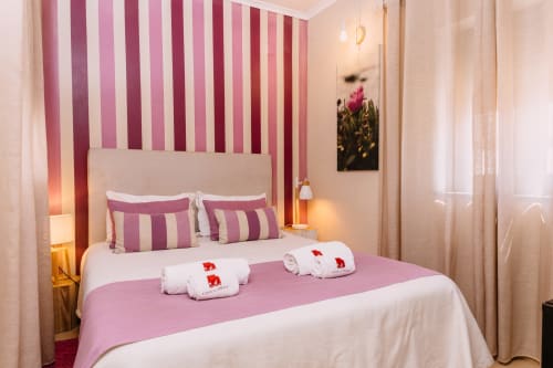 Elegant double bedroom at Casa da Praia with pink striped accent wall, white bedding, and welcoming amenities in Zambujeira