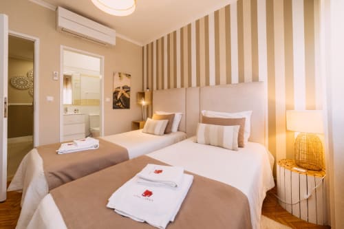 Modern double room at Casa da Praia hotel in Zambujeira do Mar with two beds, striped headboard, and ensuite bathroom
