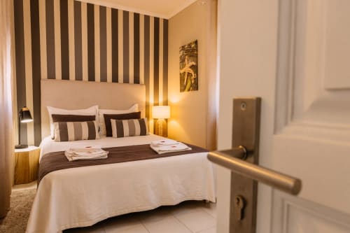 Modern Double Room at Casa da Praia in Zambujeira do Mar with striped headboard, neutral bedding, and warm lighting