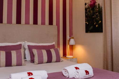 Cozy double bedroom at Casa da Praia with purple-striped bedding, rolled towels, and ambient lamp lighting