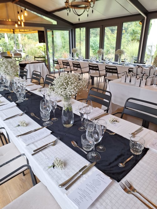 Eleganter Bankettsaal der Locanda del Sasso mit schwarzen Tischläufern, weißen Blumen, Gedeck und Gartenblick