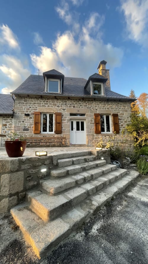 Maison en pierre avec lucarnes, volets en bois et escalier de pierre à Darazac, France