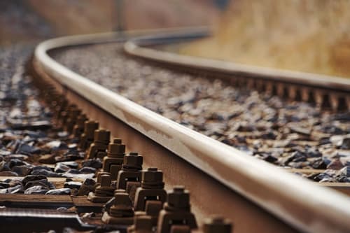 Close-up of railroad tracks with gravel ballast and metal fixtures near The Ball Alley in Stanley