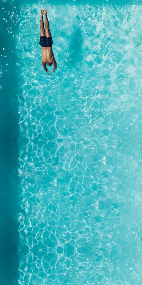 Man diving into turquoise pool water, aerial view at The Ball Alley B&B in Stanley