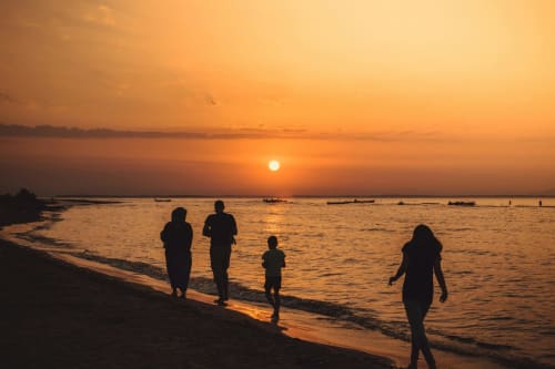 Siluetas familiares al atardecer en la playa del Hotel Estrella, Matamoros con botes y cielo dorado