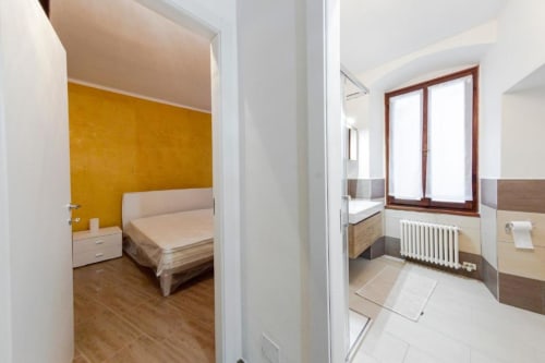 Camera da letto Dimore Verona moderna con parete in oro, pavimenti in legno e bagno ensuite con ampi infissi