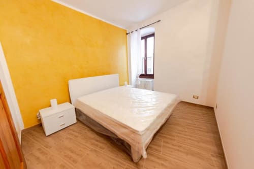 Camera da letto luminosa giallo brillante con letto queen size nell'appartamento Dimore Verona, parquet e vista dalla finestra