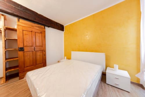 Camera luminosa all'Apartment Dimore Verona di Verona con parete gialla, letto bianco, guardaroba in legno e pavimento in legno.