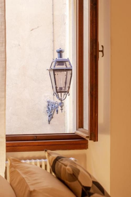 Accogliente camera da letto in appartamento a Verona con vista su lanterna storica su muro bianco, cornice in legno e cuscini