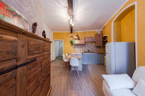 Cucina e soggiorno moderni a Dimore Verona con pareti gialle, arredi in legno e tavolo da pranzo