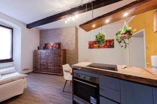 Cucina moderna a Dimore Verona con travi in legno, parete gialla e mobili rustici