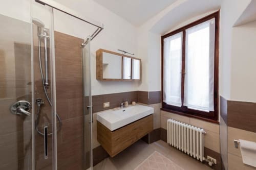 Moderno bagno a Dimore Verona con lavabo in legno, doccia walk-in e ampie finestre affacciate su Verona