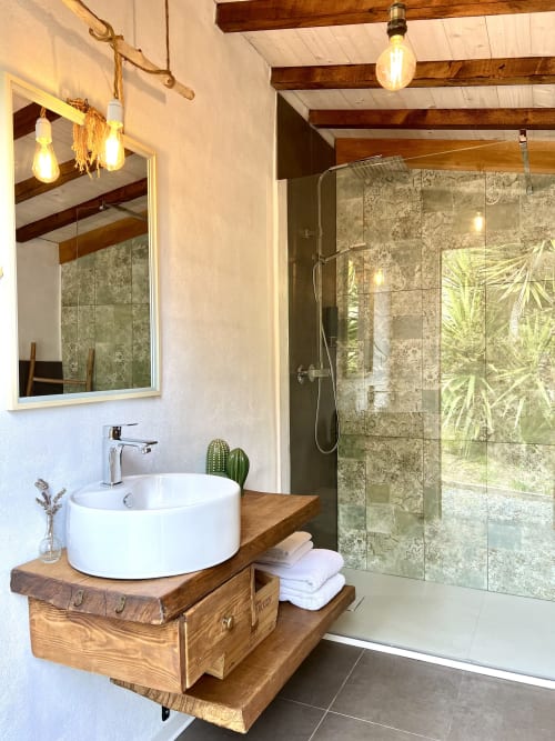 Salle de bain moderne avec lavabo blanc rond sur meuble en bois, douche vitrée et poutres bois apparentes à l'Agritusmo Stecadò