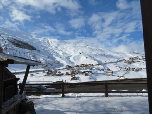 Valle di Livigno innevata con vette alpine, ringhiera in legno e villaggio di montagna dalla terrazza dell'appartamento Al Dos