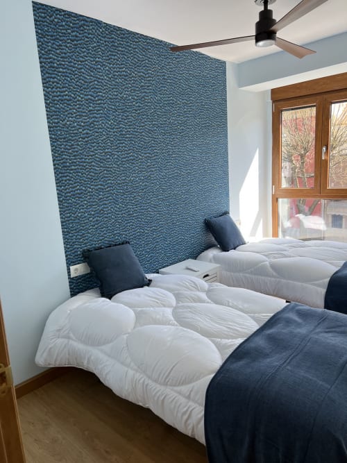 Dormitorio moderno en AlmaMaterSalamanca con camas gemelas, cabecero tapizado azul y ventanas de madera con vistas