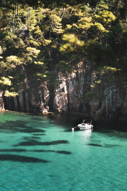 Türkisblaie Bucht mit weißem Boot, dramatische Felsklippen und Pinien in der Nähe von Ty Pals, Pals Spanien