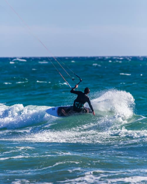 Kitesurfer reitet Wellen mit Drachen im Meer bei Pals, Spanien. Abenteuer-Wassersport bei Ty Pals.