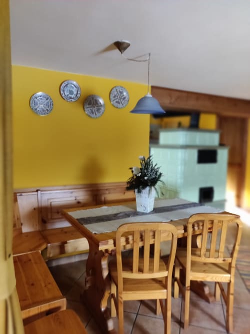 Luminosa zona pranzo dell'appartamento Al Dos a Livigno con tavolo in legno, sedie e lampada a sospensione blu