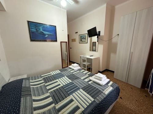 Camera accogliente al B&B Vecchie Mura di Varazze con letto a righe, TV e armadio bianco