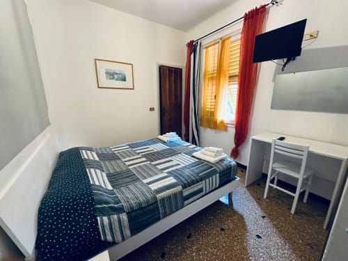 Accogliente camera da letto presso Vecchie Mura B&B a Varazze con letto matrimoniale, TV e vista sul giardino dalla finestra