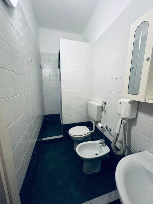 Bagno moderno di Vecchie Mura BnB a Varazze con piastrelle bianche, pavimento scuro, WC, bidet, lavabo, specchio e doccia