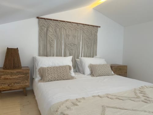 Quarto estilo boho na villa Casa Ingrina em Bordeira, com macramé na parede, roupa de cama branca, criados de madeira e vista da montanha