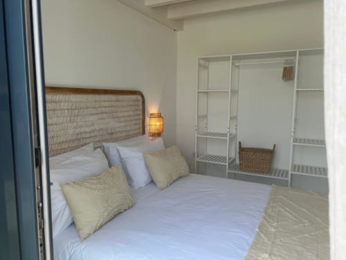 Modern bedroom at Casa Ingrina villa in Bordeira with woven headboard, white bedding, and built-in wardrobe storage.