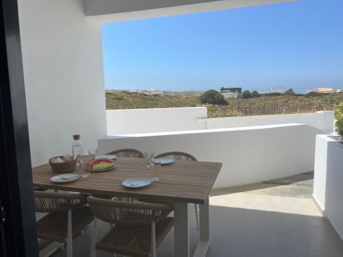 Terraço da villa Casa Ingrina em Bordeira com mesa de jantar, vista para as montanhas e arquitetura branca moderna