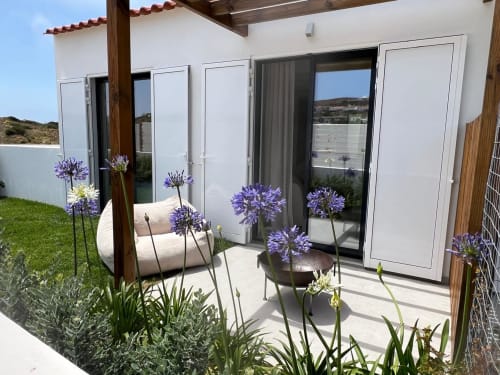 Pátio da villa Casa Ingrina em Bordeira com flores roxas de agapanto, espreguiçadeira e vistas para as montanhas