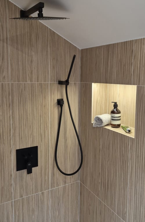 Moderne zwarte regenduche en handdouche met natuurstenen wandafwerking en ingebouwde nis in appartement Moulin Renaudiots