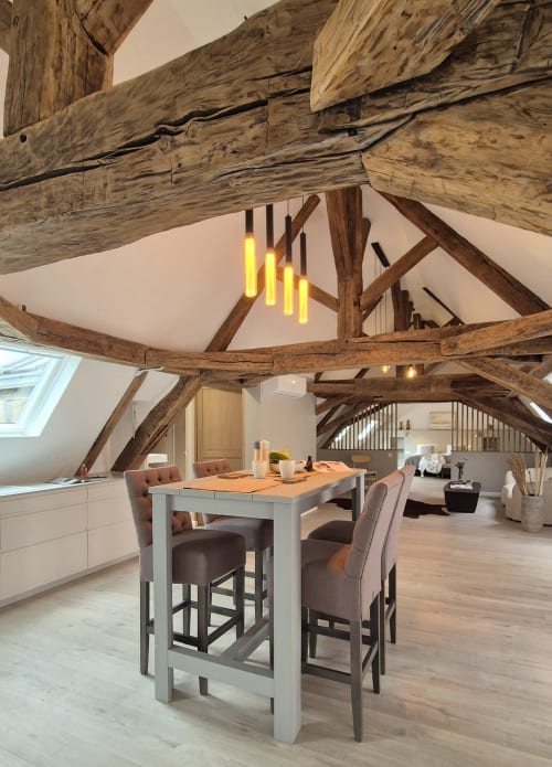 Moderne loftwoning in Moulin Renaudiots in Autun met blootgestelde houten balken, eethoek en gele hanglampjes
