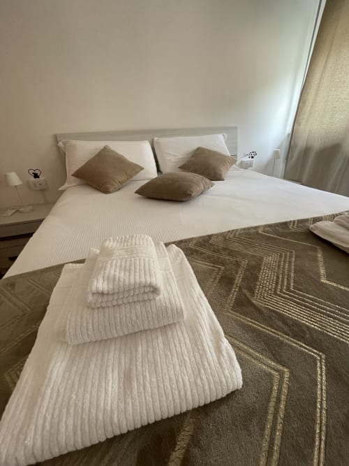 Modern bedroom at Varenna by Foot with white linens, brown pillows, and neatly arranged towels on bed
