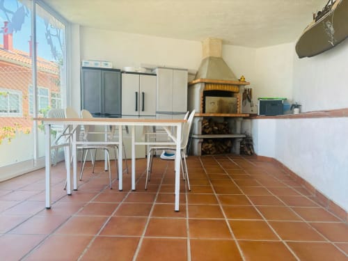Amplia terraza de cottage en Baiona con mesa de comedor, sillas, chimenea y vistas al mar a través de grandes ventanas