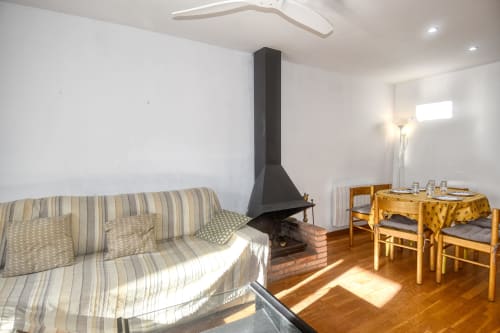 Cozy apartment in Calella with striped sofa, fireplace, wooden dining table and chairs
