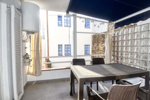 Outdoor terrace dining area at Calella apartment with table, chairs, water heater, and coastal views
