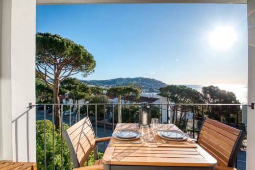 Seaside apartment balcony in Palafrugell with dining table, sea views, Mediterranean trees and coastal landscape
