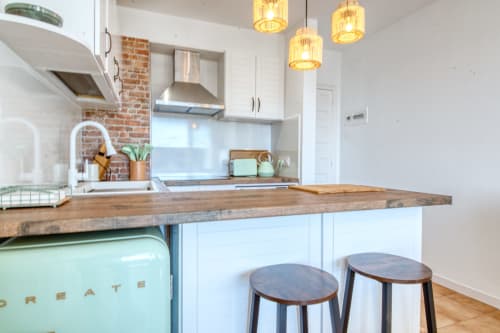Modern kitchen with wooden island, white cabinetry, mint green appliances, and pendant lighting in Palafrugell apartment.