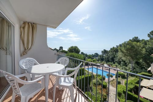 Sea view balcony at Finques Garcia Enrich, Palafrugell with white furniture, pool and Mediterranean coast visible