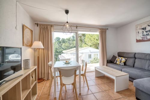 Modern apartment living room with dining area, sea views, TV, sofa, and access to pool at Finques Garcia Enrich, Palafrugell
