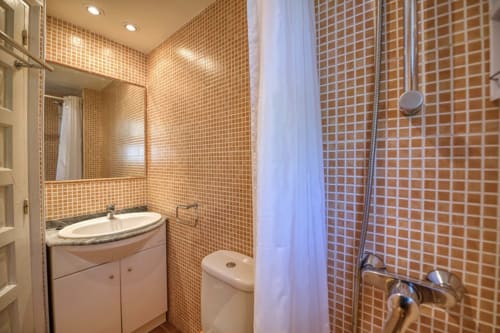 Modern bathroom with orange mosaic tiles, sink vanity, toilet, and shower with curtain at Finques Garcia Enrich apartment,
