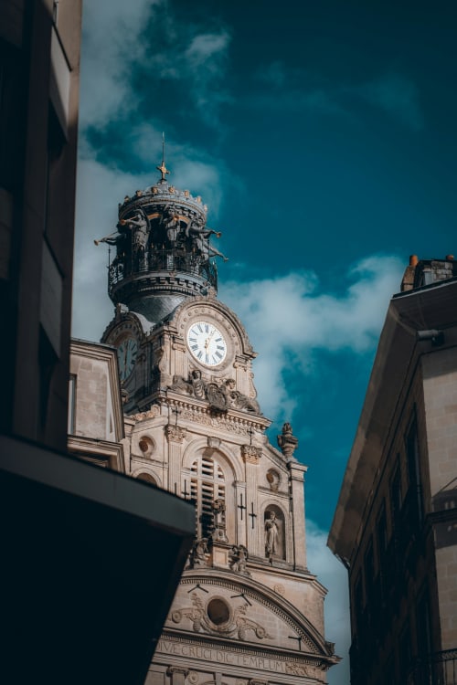 Tour d'horloge historique avec façade en pierre ornementée sous un ciel bleu, Sainte-Luce-sur-Loire