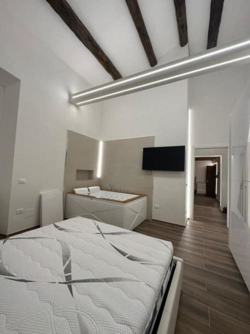 Camera moderna all'Enjoy House Bracciano con letto matrimoniale, bagno spa, TV a schermo piatto e travi in legno a vista